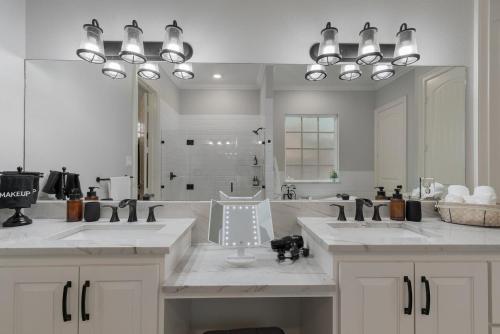 Un baño con dos lavabos y un espejo grande. en Modern 4BR Retreat, Hot Tub, Game Room near DFW, en Irving