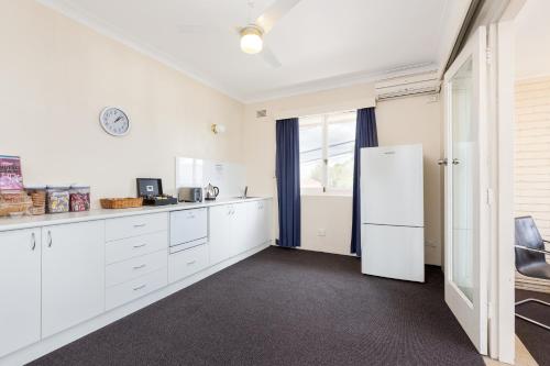 a kitchen with white cabinets and a refrigerator at Blue Gum Hotel in Hornsby
