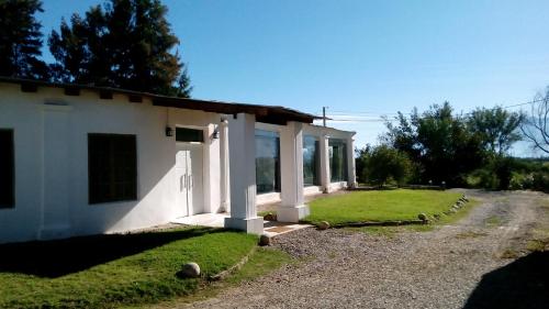 een wit gebouw met een grasveld naast een weg bij Posada Nocenta Pisetta in Chilecito