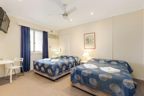 1 dormitorio con 2 camas, escritorio y mesa en Blue Gum Hotel en Hornsby