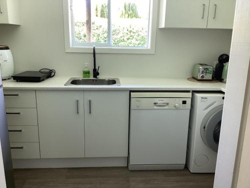 a kitchen with a sink and a washing machine at Tranquille in Tauranga in Tauranga