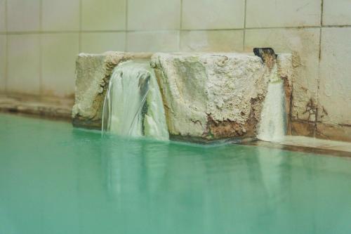 a waterfall in a pool of water in a building at Yoshidaya in Zao Onsen