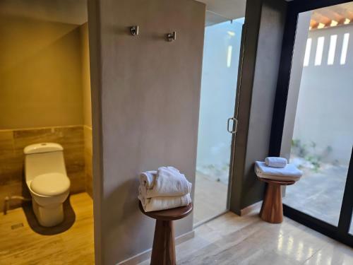 a bathroom with a toilet and a stool with towels at Hotel Flores de Sal-Valle de Guadalupe in Valle de Guadalupe