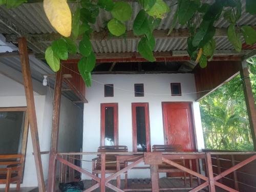 a house with red doors and a balcony at Yohana Cottage in Tual