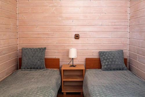 - 2 lits dans une chambre avec une table et une lampe dans l'établissement Holiday Home in Dziwnówek near Baltic Sea, à Dziwnówek