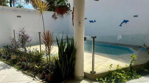 a swimming pool with plants in front of a building at Nosso Lar in Porto Seguro