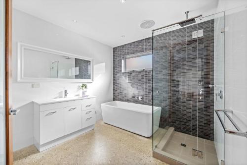Hamilton HillにあるStylish 4-Bedroom Coastal Family-Friendly Retreatのシャワー、浴槽、洗面台を備えたバスルーム