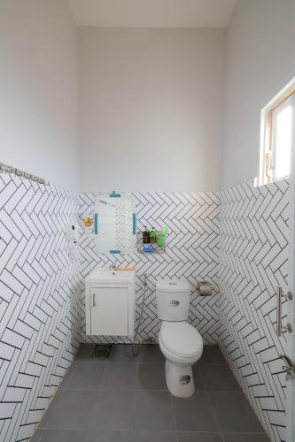 a bathroom with a toilet and a tiled wall at Happy Bear Hostel Phu Quoc in Phu Quoc