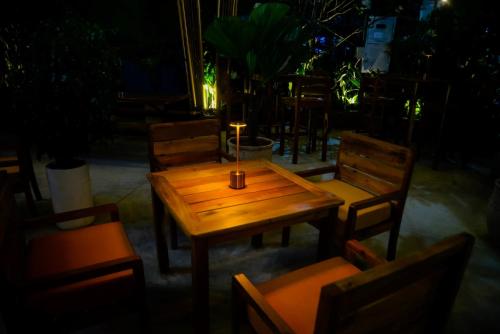 a wooden table and chairs with a candle on it at Happy Bear Hostel Phu Quoc in Phu Quoc