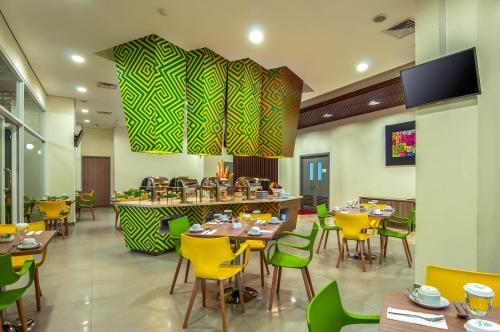 a dining room with tables and chairs and a tv at KHAS Makassar Hotel in Makassar
