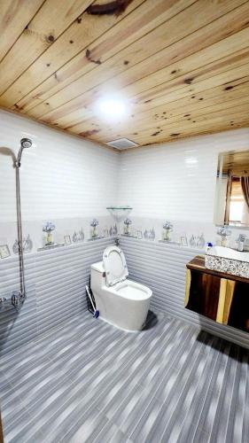 a bathroom with a toilet and a wooden ceiling at Chuyện Của Mây Villa in Ấp Ða Lôc