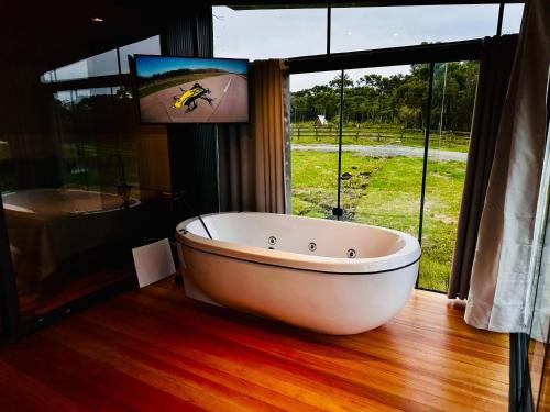 a large white bath tub in a room with a window at Cabana Black BIRD l, morro da igreja Urubici SC in Urubici