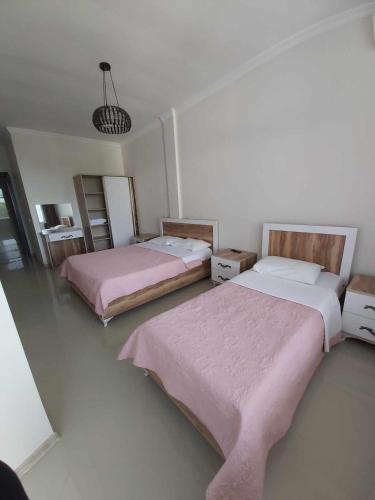 two beds in a white room with pink sheets at Goga Guest House in Kvariati