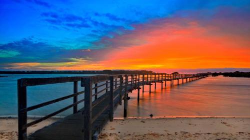 a pier stretches out into the water at sunset at Boardwalk Bungalow - pristine ocean views in Urunga