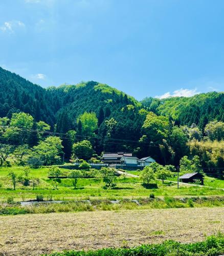 a house in a field in front of a mountain at Kuon 一棟貸し(素泊まり)北欧サウナ＋ガーデン付き古民家 in Kisa