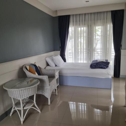a bedroom with a bed and a chair and a window at โรงแรม ริเวอร์บรีซ เชียงแสน River Breeze Chiangsean in Chiang Saen