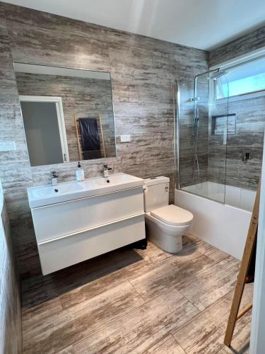 a bathroom with a sink and a toilet and a mirror at Large Cowes Getaway- Fireplace, Near the Beach in Cowes