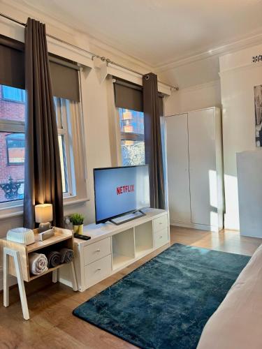 a living room with a flat screen tv on a cabinet at The Prestige Suite - London in London