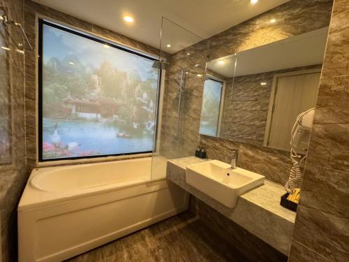 a bathroom with a tub and a sink and a large window at Putin Hotel Nha Trang in Nha Trang