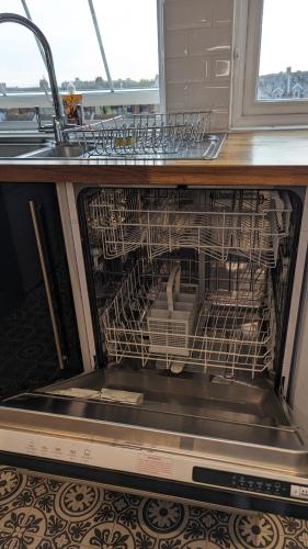 a dishwasher with dishes in it under a sink at Stylish Condo on Victorian Seafront, Voyagers Rest Bexhill in Bexhill