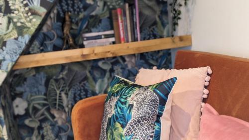 a couch with a pillow on it with a book shelf at Stylish Condo on Victorian Seafront, Voyagers Rest Bexhill in Bexhill