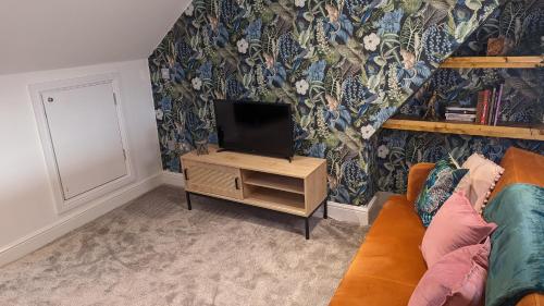 a living room with a tv on a wooden stand at Stylish Condo on Victorian Seafront, Voyagers Rest Bexhill in Bexhill