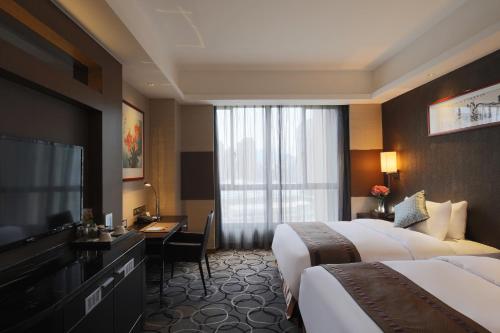 una camera d'albergo con due letti e una televisione di Millennium Hotel Fuqing a Fuqing