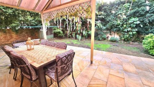 a patio with a table and chairs under an umbrella at Hills Bed & Breakfast in Pennant Hills
