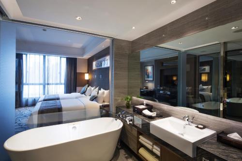 a bathroom with a tub and a bed and a sink at Millennium Hotel Fuqing in Rongcheng