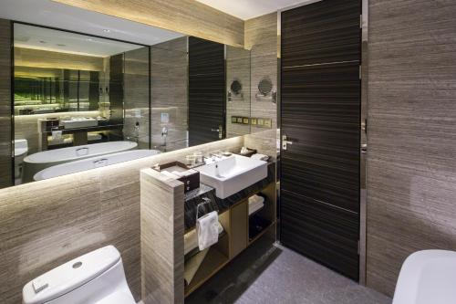 a bathroom with a sink and a toilet and a mirror at Millennium Hotel Fuqing in Rongcheng