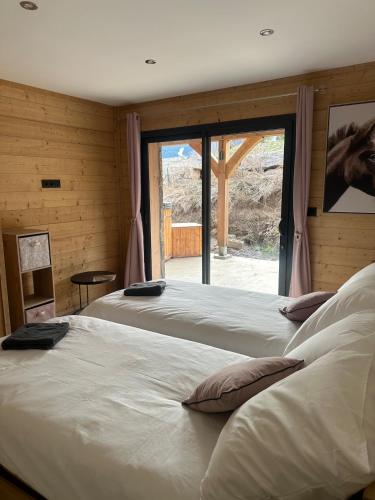 deux lits dans une chambre avec une grande fenêtre dans l'établissement l'étoile du cambre, à La Cabanasse