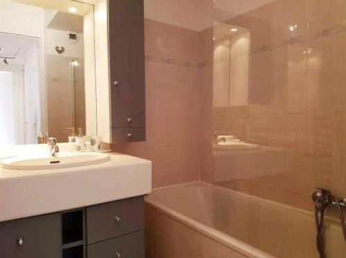 une salle de bain avec un lavabo, une baignoire et un miroir dans l'établissement Centre Cannes Suquet, à Cannes