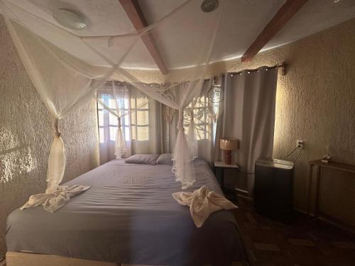 a bedroom with a white canopy bed with a window at Cabañas y hospedaje Sol y Luna Motul in Motul de Felipe Carrillo Puerto