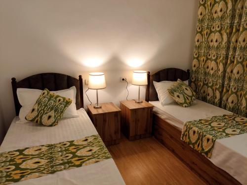 two beds in a room with two lamps at Sahro Hotel in Bukhara