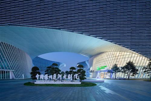 a large building with a sign in front of it at Holiday Inn Express Yangzhou Grand Canal Theatre in Yangzhou