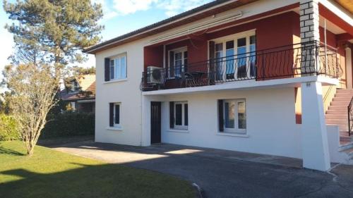 a white and red house with a balcony at Logement paisible avec jardin, accès plain pied sans escalier, parking et WiFi in Roche-la-Molière