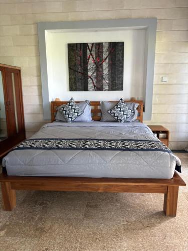 a bedroom with a large bed with a wooden frame at villa Angin in Munggu