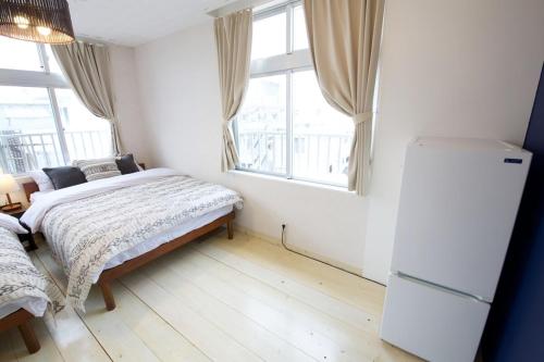 a bedroom with a bed and a refrigerator and windows at Itomann IN in Sunja