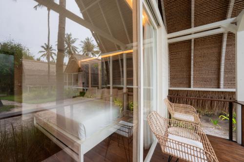 a screened in porch with two chairs and a table at Hotel Lumi Gili Trawangan in Gili Trawangan