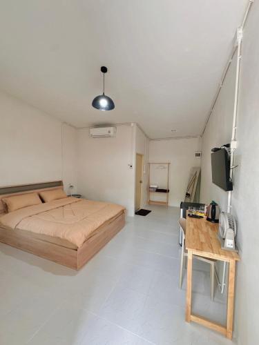a bedroom with a bed and a desk and a tv at NP โฮมสเตย์ นอนเต็นท์ติดแอร์ in Ban Kaeng Manao