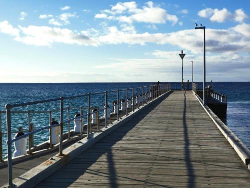 a pier with people sitting on it next to the ocean at Entire guesthouse walking to beach in Rosebud