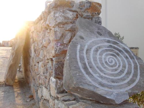 una escultura de piedra de una espiral en una pared de piedra en Speires suites, en Iraklia