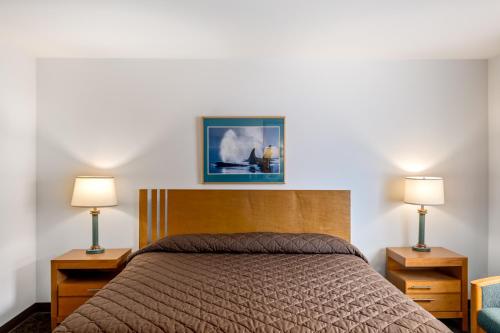 a bedroom with a bed with two lamps and a picture on the wall at Breeze Inn Hotel in Seward