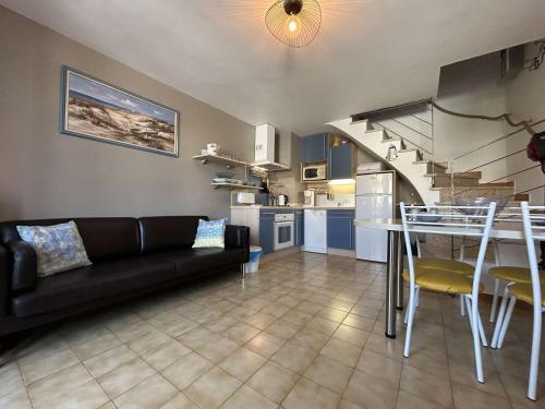 un salon avec un canapé noir et une cuisine dans l'établissement Appartement Duplex P3 Climatisé Proche Plage - FR-1-250-303, au Grau-du-Roi