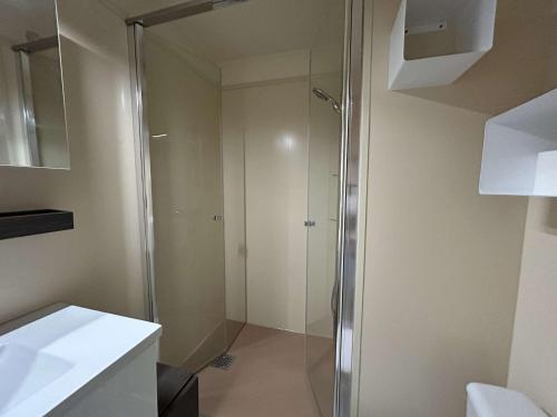 une douche avec une porte vitrée dans une salle de bain dans l'établissement Appartement Duplex P3 Climatisé Proche Plage - FR-1-250-303, au Grau-du-Roi