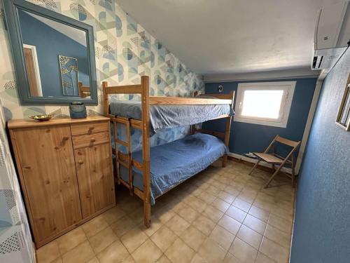 Cette petite chambre comprend des lits superposés et un miroir. dans l'établissement Appartement Duplex P3 Climatisé Proche Plage - FR-1-250-303, au Grau-du-Roi