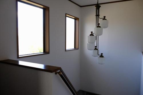 a room with a staircase with two windows and a chandelier at Minpaku-K in Nasushiobara