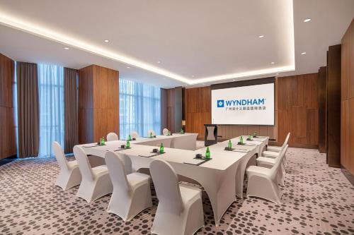 a meeting room with a long table and white chairs at Wyndham Hotel Guangzhou Huangbian Metro Branch - Free shuttle bus to Canton Fair in Guangzhou