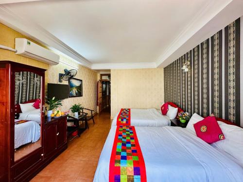 a hotel room with two beds and a desk at Hà Giang Hotel Sapa in Sa Pa