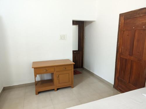 a room with a wooden table and a door at Milu Homes in Thirunelli